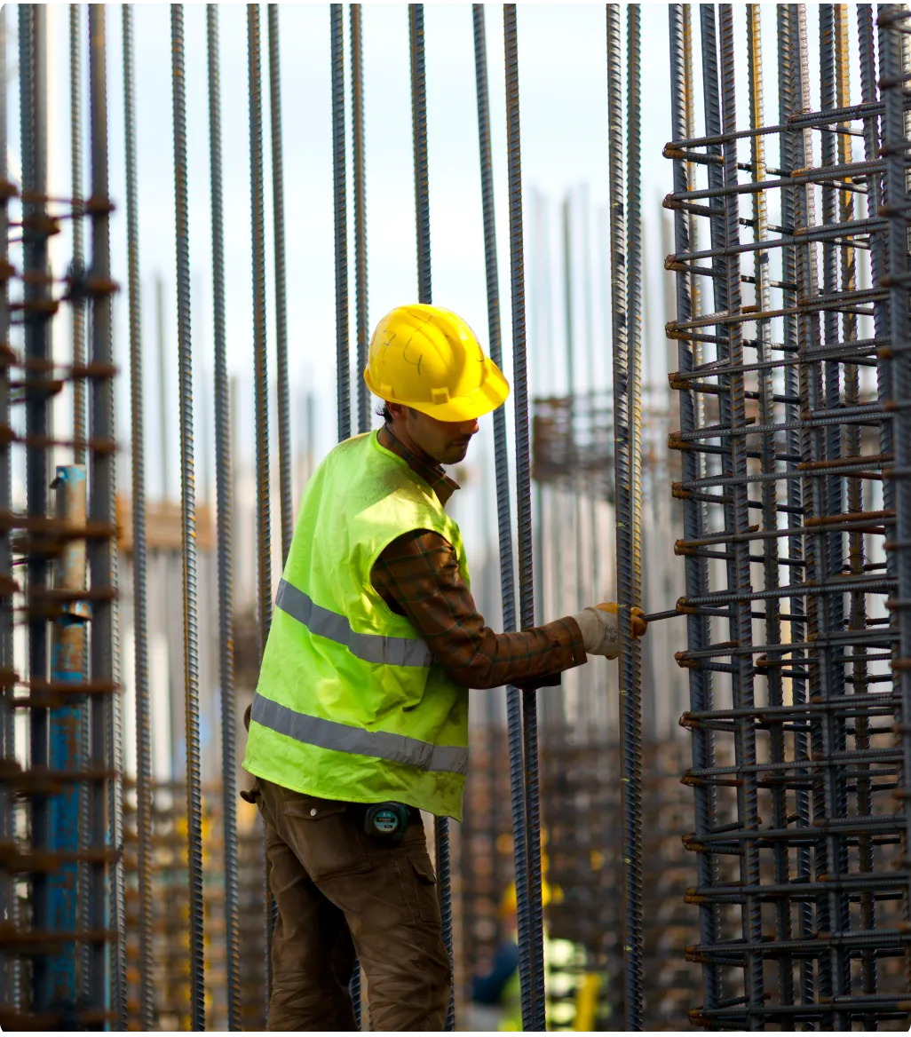 A man in a hard hat and safety vest working on a construction site.
